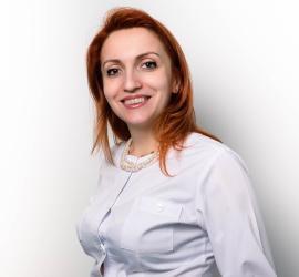 Dr. Aristide, dentist din București, zâmbind în uniformă albă, cu părul roșcat și un colier elegant.