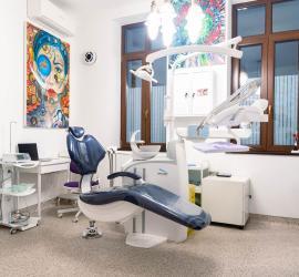 Scaun de dentist modern într-un cabinet stomatologic, cu echipamente și decor colorat pe perete.