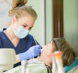 Un dentist examinează un copil în timpul unei consultații dentare.