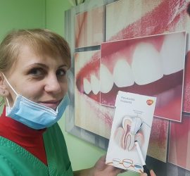 Asistentă dentară ținând un material informativ despre sănătatea orală, purtând mască de protecție.