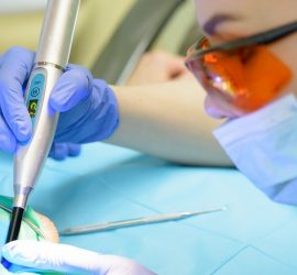 Medic stomatolog folosind un instrument de tratament dentar pe un pacient în timpul unei proceduri.