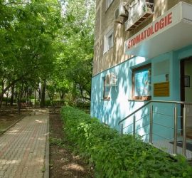 Clădire stomatologică cu un semn pe fațadă și o intrare cu rampă pentru accesibilitate.