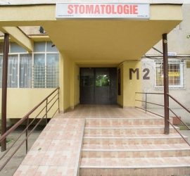 Intrarea unei clinici de stomatologie cu un semn deasupra ușii de acces.