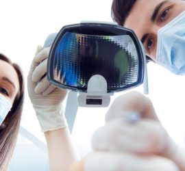 Doi medici, un bărbat și o femeie, purtând măști de protecție, examinând un instrument medical.