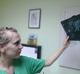 Medic stomatolog examinând radiografii dentare într-un cabinet medical.