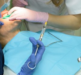 Un pacient în timpul unei proceduri dentare, cu un medic dentist administrând anestezie locală.