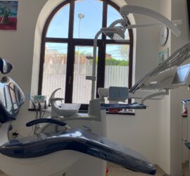 Scaun de stomatologie albastru și alb, dotat cu echipamente dentare într-un cabinet.