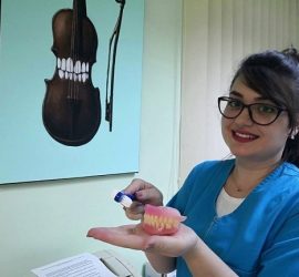 O persoană care aplică o soluție de curățare pe o proteză dentară în cabinetul stomatologic.