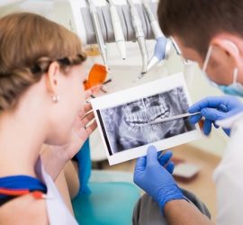 Medic stomatolog arătând o radiografie dentară unei paciente în timpul unei consultații.