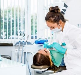 O asistentă dentară îngrijind un pacient într-un cabinet stomatologic modern.