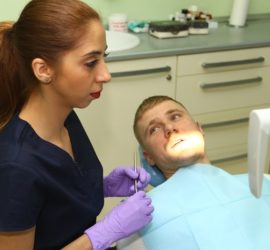 Dentist examining a patient in a dental clinic with dental tools in hand.