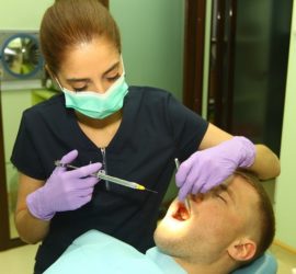 Asistent medical stomatologic aplicând anestezie unui pacient în cabinetul dentar.