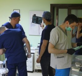 Patru membri ai echipei medicale în timpul unei proceduri stomatologice într-un cabinet.