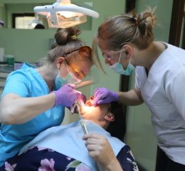 Medic stomatolog și asistent dentar examinând un pacient în cabinetul stomatologic.