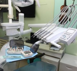 Unit dentar cu diverse instrumente de tratament și un set de accesorii pe o masă de lucru.