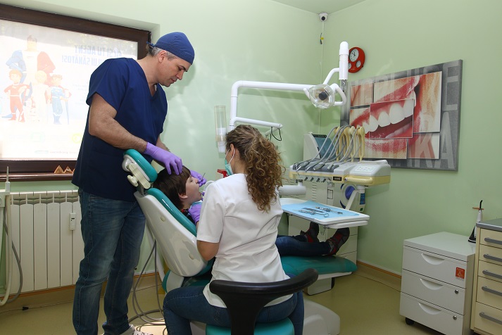 Medic stomatolog cu mănuși examinând un copil într-un cabinet stomatologic.