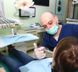 Medic stomatolog aplicând anestezie unui pacient în cabinetul stomatologic.