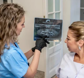 Medic stomatolog explica pe o radiografie panoramica, pacientului, planul de tratament