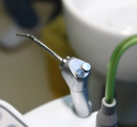 Instrument de dentisterie cu duză metalică și tub de alimentare cu apă.