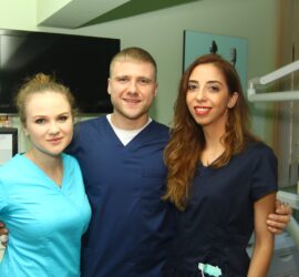 Trei membri ai unei echipe medicale pozând împreună, îmbrăcați în uniforme de lucru.