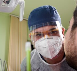 Medic stomatolog purtând echipament de protecție, examinând un pacient în cabinetul stomatologic.