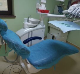 Scaun de dentist acoperit cu o folie de protecție albastră într-un cabinet stomatologic.