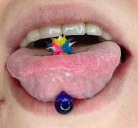 Aristide – piercing lingual cu bijuterie colorată pe limbă, scobitura bucala evidențiată, costum dentar, bijuterii orale în context medical.
