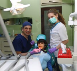 Medic stomatolog și asistentă lucrând cu un pacient în cabinetul dentar.