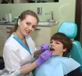 Medic stomatolog cu mănuși purtând un instrument dentar în gura unui copil la cabinetul stomatologic.