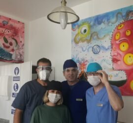 Patru membri ai personalului medical purtând măști și echipament de protecție într-un mediu clinic.
