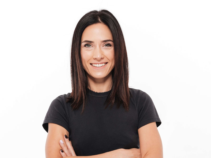 Femeie cu părul lung și negru, îmbrăcată în tricou negru, zâmbind și având brațele încrucișate.