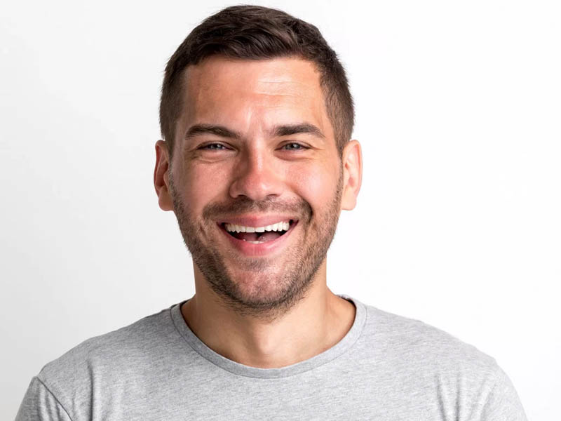 Bărbat tânăr cu păr scurt și zâmbet larg, purtând un tricou gri simplu.