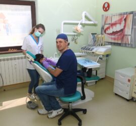 Medic stomatolog în uniformă, tratând un pacient pe scaunul stomatologic într-un cabinet modern.