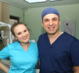 Două persoane în uniformă medicală zâmbind pentru fotografie într-un cabinet medical.