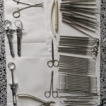 Pulpotomia Set de instrumente stomatologice aranjate pe o suprafață albă, inclusiv clești și oglinzi.