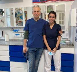 Două persoane îmbrăcate în uniforme medicale stând într-un cabinet stomatologic.