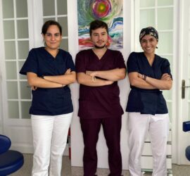 Trei membri ai echipei medicale îmbrăcați în uniforme, stând cu brațele încrucișate.