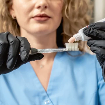 Femeie cu par blond ondulat pune pasta de dinti parodontax pe periuta dentara