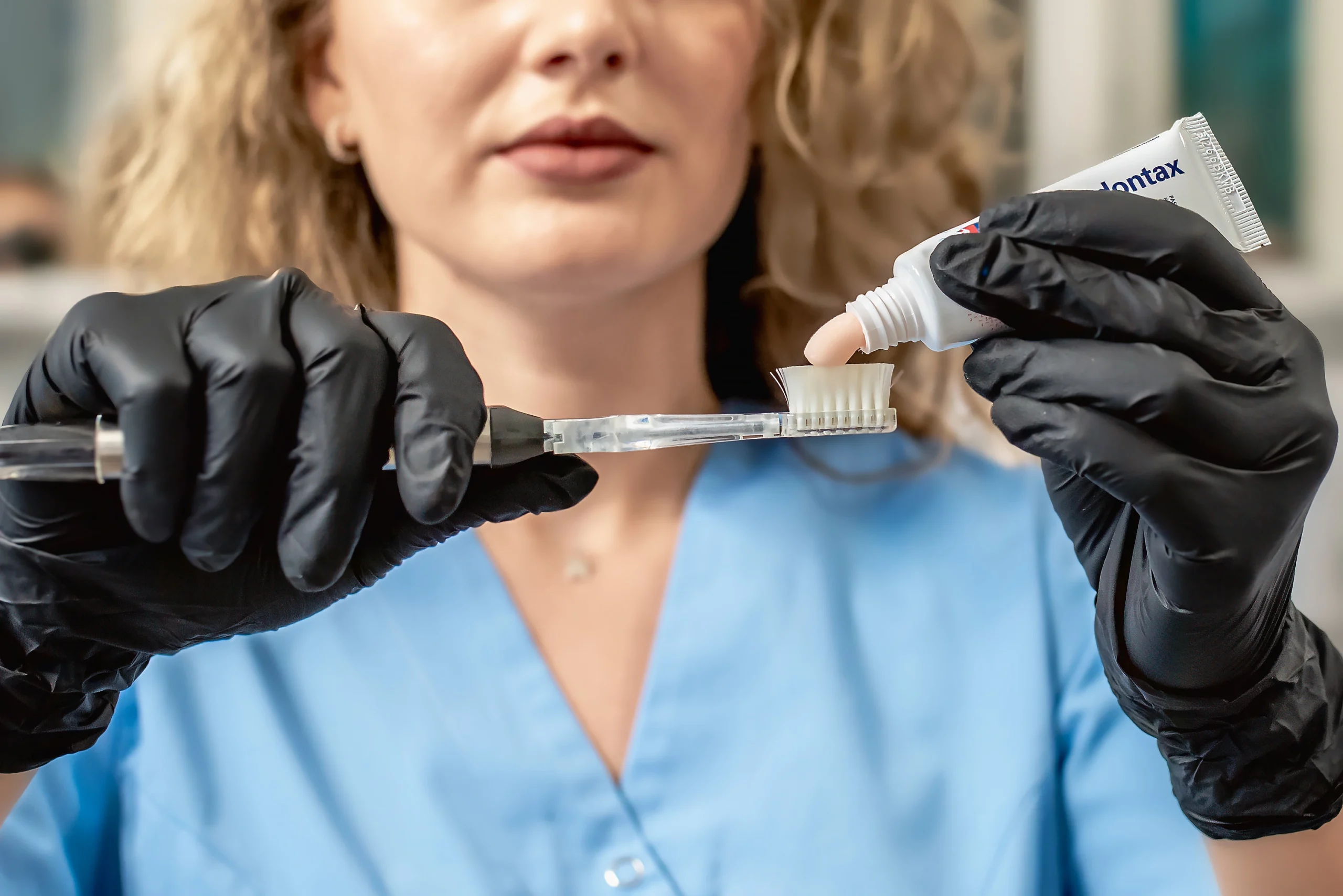 Femeie cu par blond ondulat pune pasta de dinti parodontax pe periuta dentara