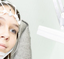 Tânără cu electrozi pe cap, supusă unei electroencefalograme într-un mediu clinic.