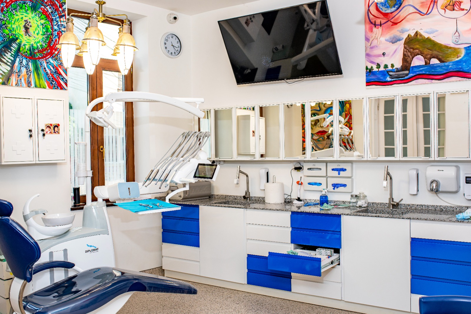 Interiorul unui cabinet stomatologic cu echipamente și mobilier alb și albastru.