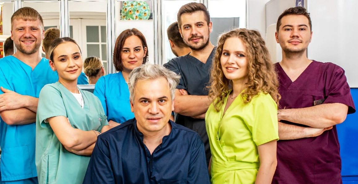 Grup de șase persoane din echipa Dr. Aristide, îmbrăcate în uniforme medicale.