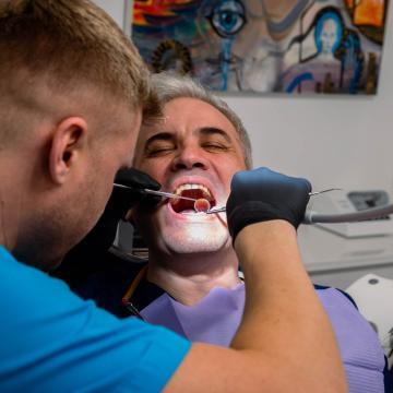 Medic stomatolog examinând un pacient în timpul unei consultații dentare.