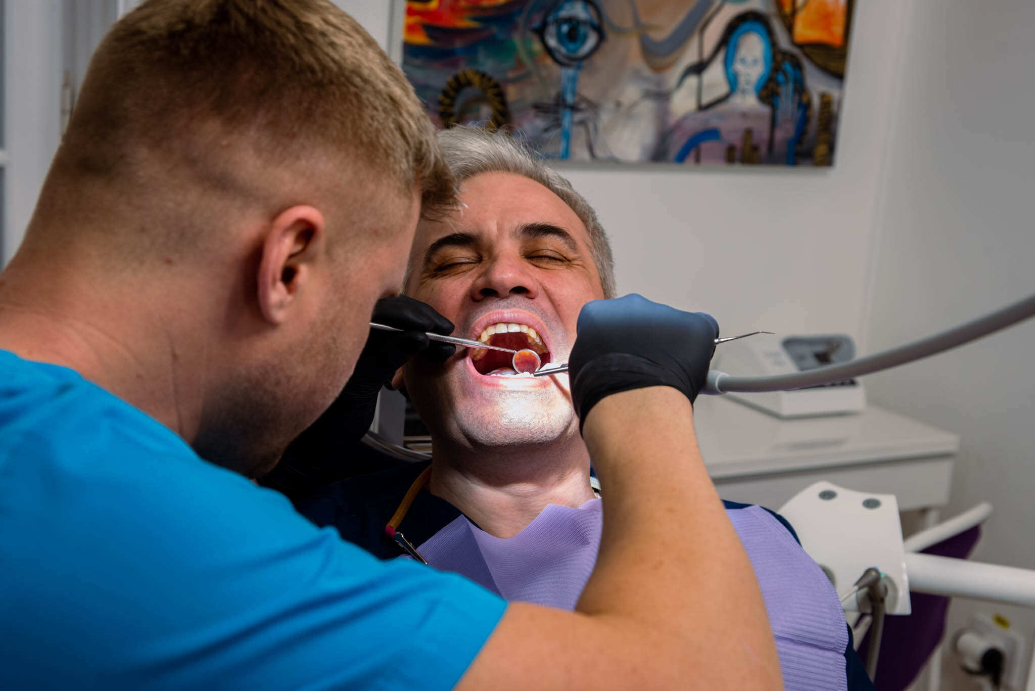 Medic stomatolog examinând un pacient în timpul unei consultații dentare.