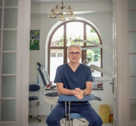 Dr Aristide Dan Adrian cu ochelari, in uniforma medicală, in cabinetul stomatologic