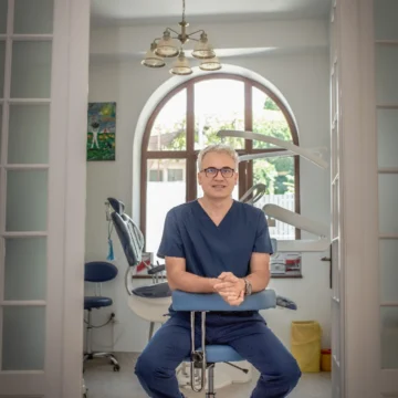 Dr Aristide Dan Adrian cu ochelari, in uniforma medicală, in cabinetul stomatologic