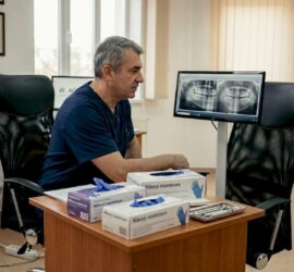 Medicul dentist analizează o radiografie dentară pentru a evalua sănătatea dinților.