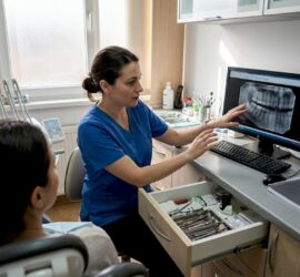Medicul stomatolog discută cu pacientul în cabinet, oferindu-i sfaturi și răspunsuri la întrebările legate de sănătatea dentară.