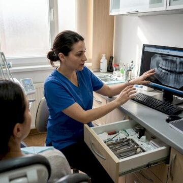 Medicul stomatolog discută cu pacientul în cabinet, oferindu-i sfaturi și răspunsuri la întrebările legate de sănătatea dentară.