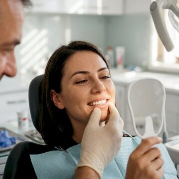 Medicul stomatolog își consultă pacientul în cabinetul său.